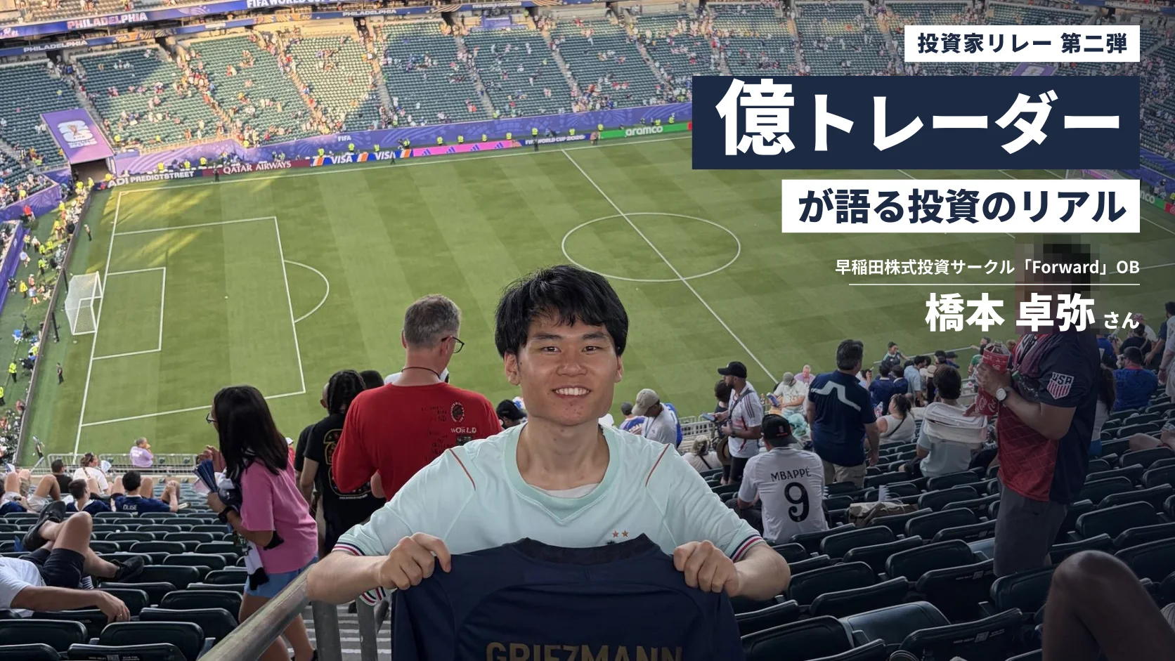 サッカースタジアムの観客席で、フランス代表のユニフォームを手に笑顔を見せる橋本さん